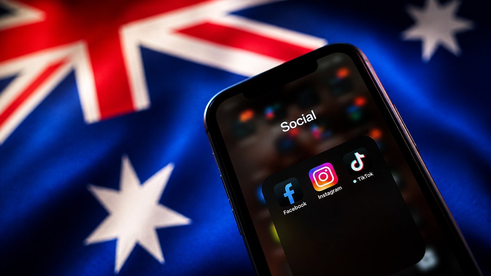 Un smartphone affichant les applications Facebook, Instagram et TikTok, devant un drapeau australien flou